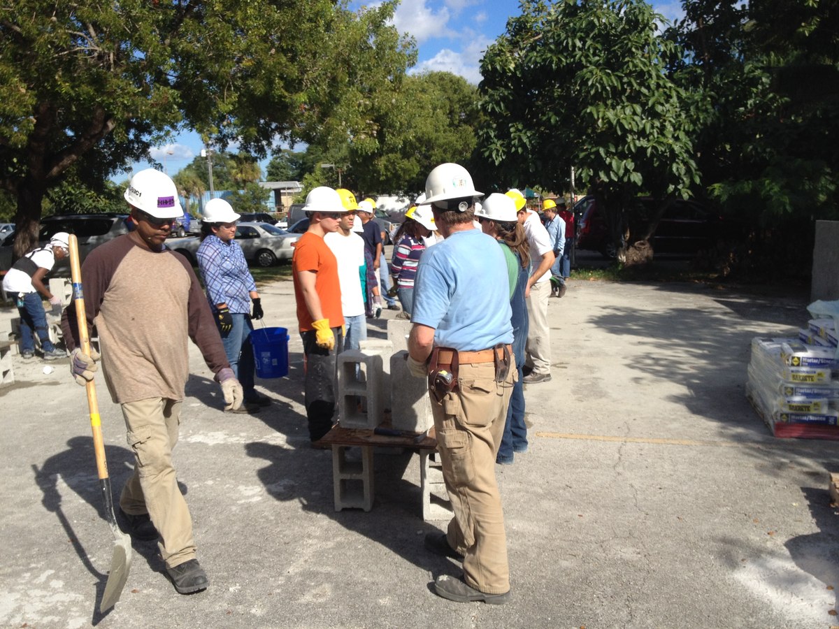 Construction crew with hard hats around CMU blocks during a team training/build event.